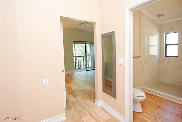 bathroom with toilet, tiled shower, hardwood / wood-style flooring, and vaulted ceiling