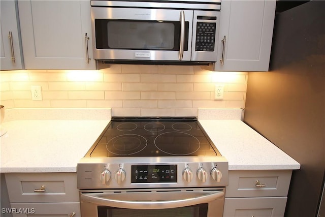 kitchen featuring light stone countertops, appliances with stainless steel finishes, tasteful backsplash, and gray cabinetry