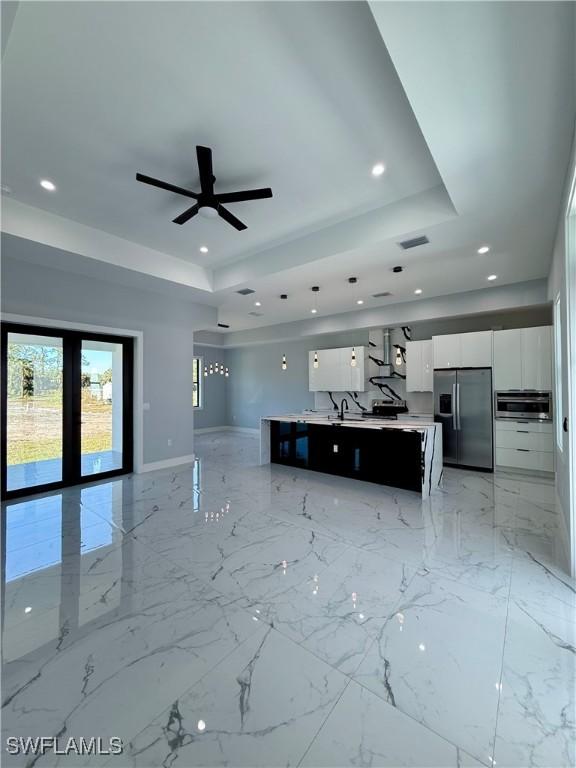 unfurnished living room with french doors, a raised ceiling, and ceiling fan