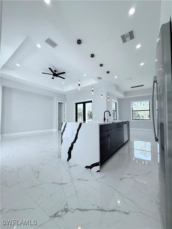 kitchen with a tray ceiling, stainless steel fridge, and plenty of natural light