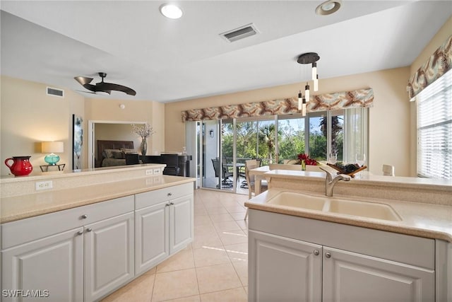 kitchen with light tile patterned flooring, sink, white cabinets, and ceiling fan