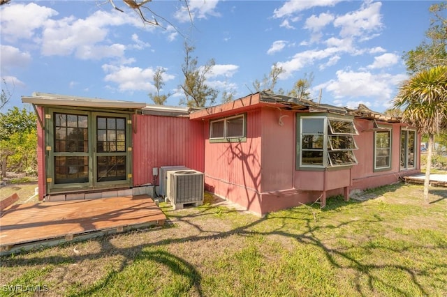 back of house with cooling unit, a wooden deck, and a lawn