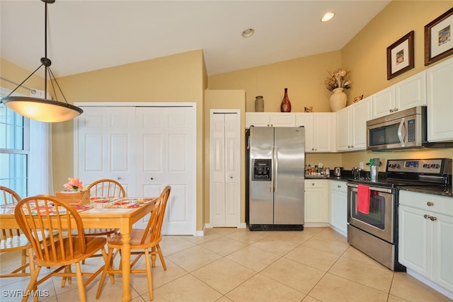 kitchen with white cabinetry, hanging light fixtures, lofted ceiling, light tile patterned flooring, and appliances with stainless steel finishes