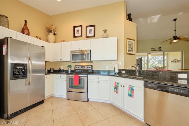 kitchen featuring dark stone counters, stainless steel appliances, ceiling fan, light tile patterned floors, and white cabinets