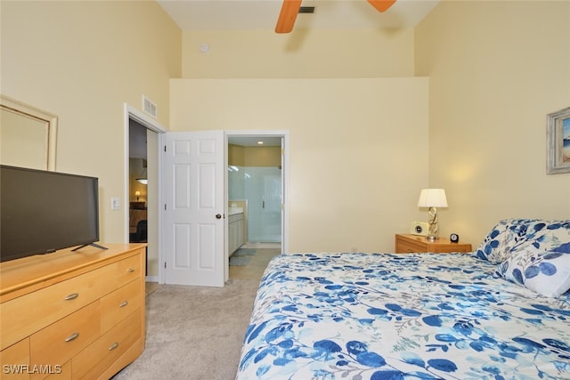 bedroom with ensuite bath, light carpet, ceiling fan, and a high ceiling