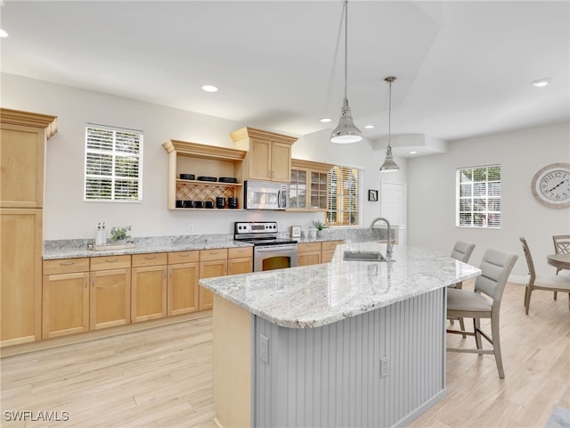 kitchen with a center island with sink, appliances with stainless steel finishes, light stone counters, a breakfast bar, and sink