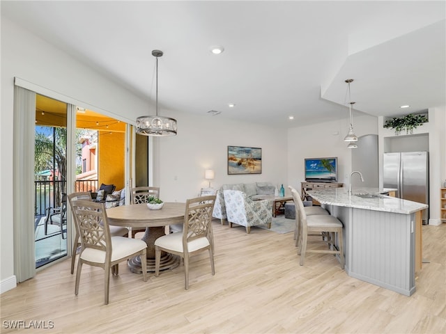 dining area with sink, a chandelier, and light hardwood / wood-style flooring