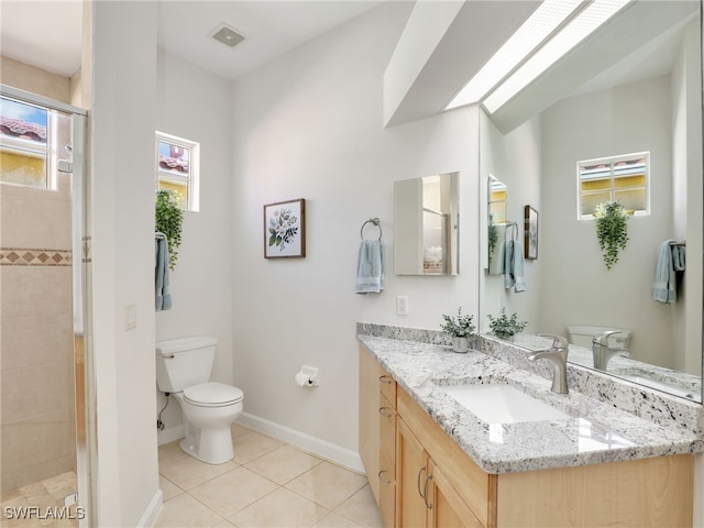 bathroom with toilet, tile patterned floors, vanity, and a shower with shower door