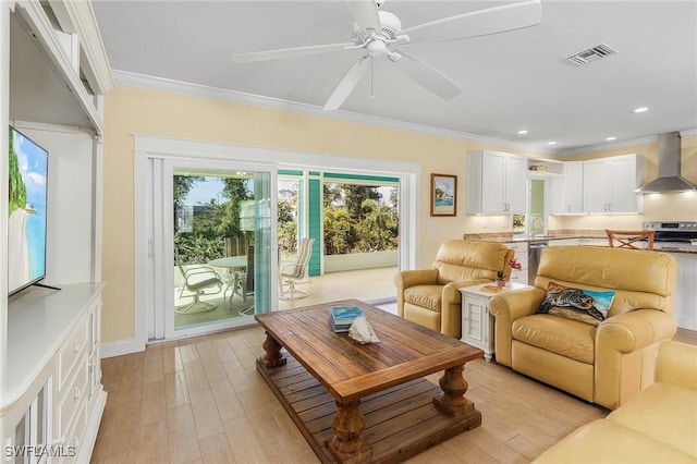 living room featuring ceiling fan, ornamental molding, sink, and light hardwood / wood-style flooring