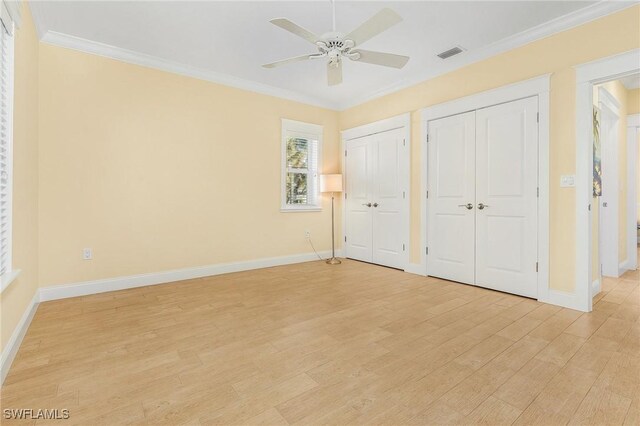 unfurnished bedroom featuring multiple closets, ceiling fan, light hardwood / wood-style flooring, and ornamental molding