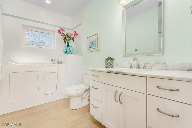 bathroom featuring a bathing tub, vanity, toilet, and wood-type flooring