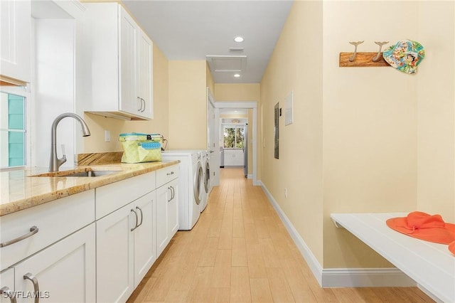 kitchen with light stone counters, sink, light hardwood / wood-style flooring, white cabinets, and independent washer and dryer