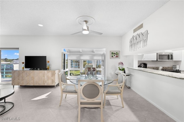 tiled dining area featuring a textured ceiling and ceiling fan