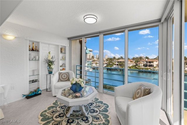 living room featuring floor to ceiling windows, a water view, a textured ceiling, and light tile patterned flooring