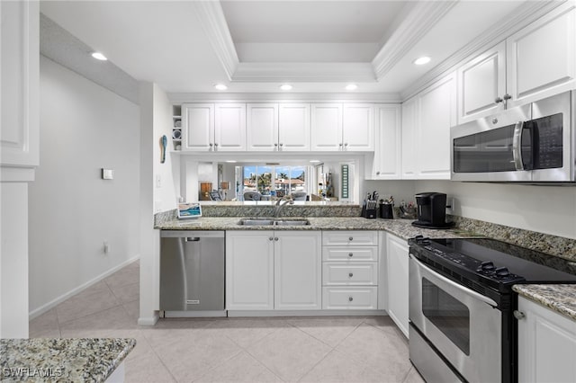 kitchen with white cabinets, stainless steel appliances, a tray ceiling, and sink