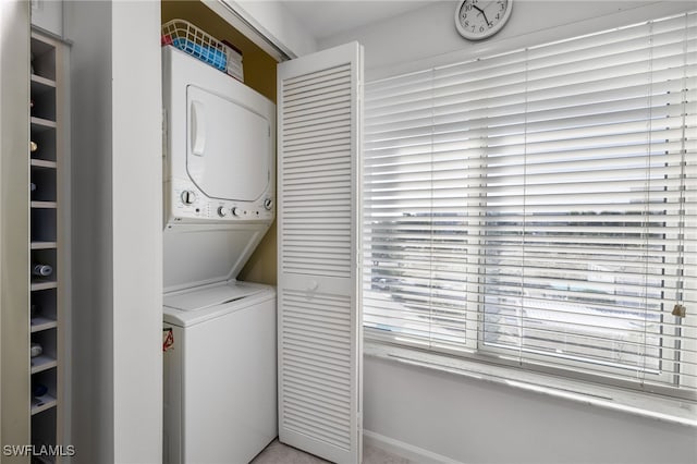 clothes washing area with plenty of natural light and stacked washer and dryer