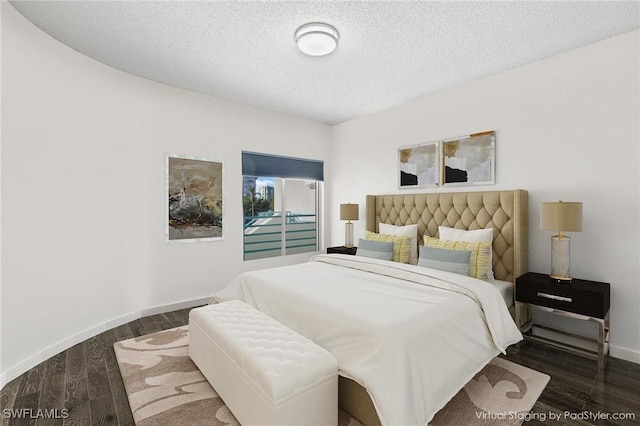 bedroom with a textured ceiling and dark wood-type flooring