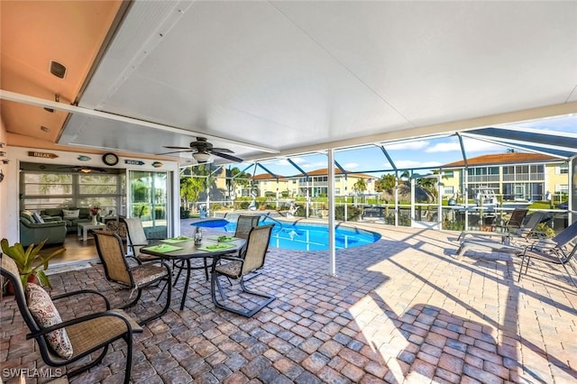 view of pool with a water view, a lanai, a patio area, and ceiling fan