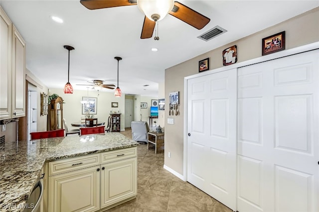 kitchen with cream cabinetry, pendant lighting, and light stone countertops