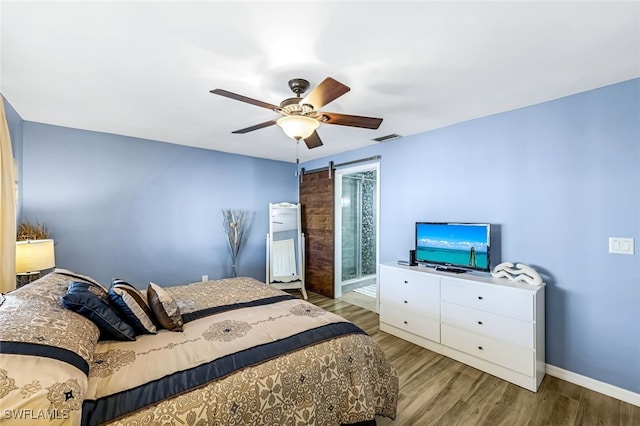 bedroom with a barn door, ceiling fan, and wood-type flooring