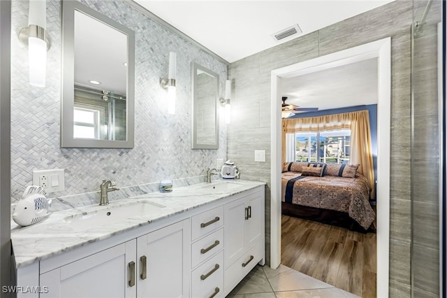 bathroom with ceiling fan, vanity, wood-type flooring, and tile walls