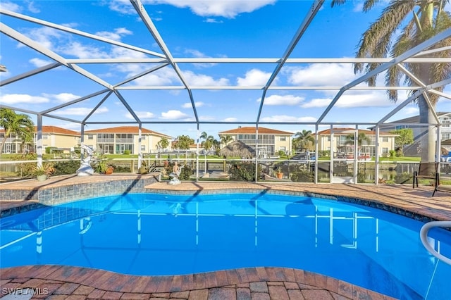 view of swimming pool featuring a water view, glass enclosure, and a patio area