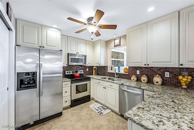 kitchen with sink, ceiling fan, tasteful backsplash, light stone counters, and stainless steel appliances