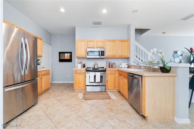 kitchen with light tile patterned flooring, light brown cabinets, stainless steel appliances, and sink