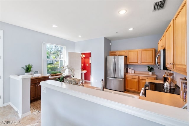 kitchen with light tile patterned flooring, sink, kitchen peninsula, and stainless steel appliances