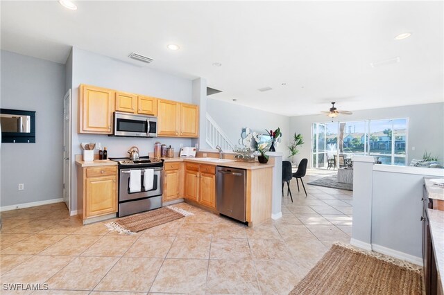 kitchen with ceiling fan, sink, stainless steel appliances, light brown cabinetry, and light tile patterned floors