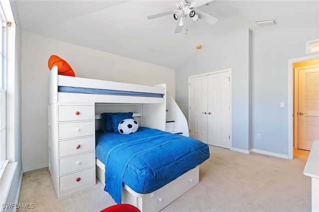 carpeted bedroom with a closet, vaulted ceiling, and ceiling fan