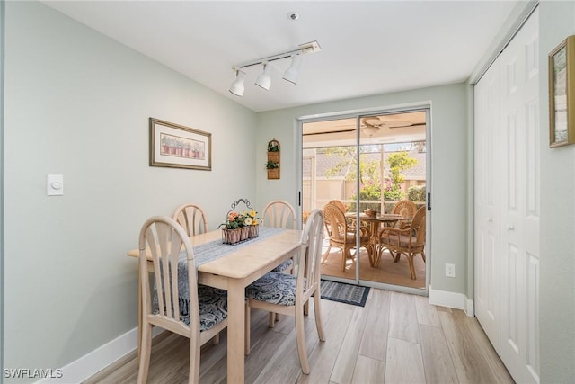 dining area with light wood-type flooring and track lighting