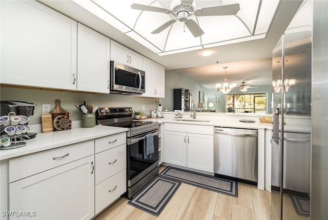 kitchen with pendant lighting, sink, appliances with stainless steel finishes, white cabinetry, and kitchen peninsula