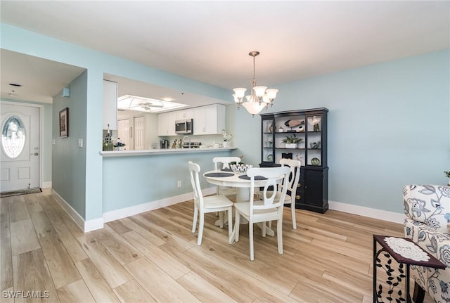 dining room with light hardwood / wood-style floors and an inviting chandelier