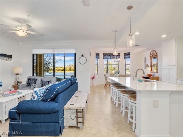 living room with ceiling fan, a wealth of natural light, ornamental molding, and sink