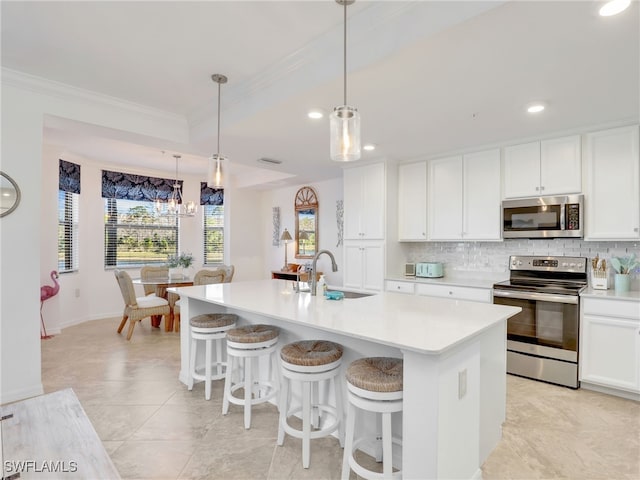 kitchen featuring white cabinets, decorative backsplash, a center island with sink, and appliances with stainless steel finishes