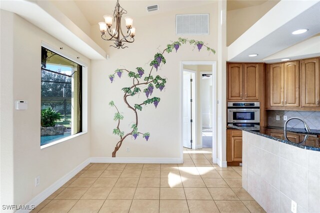 kitchen featuring decorative light fixtures, dark stone countertops, oven, lofted ceiling, and light tile patterned flooring