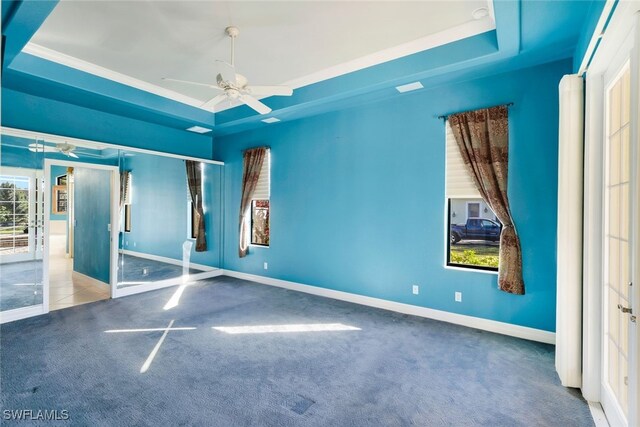 carpeted empty room featuring a raised ceiling, ceiling fan, and ornamental molding