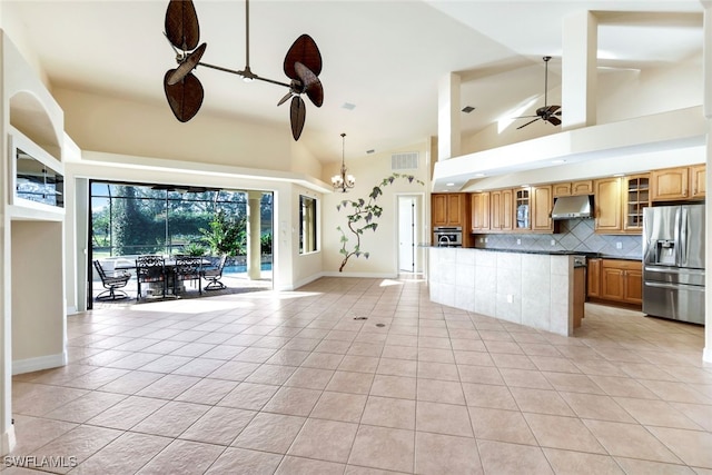 kitchen with high vaulted ceiling, ceiling fan with notable chandelier, decorative backsplash, light tile patterned flooring, and stainless steel appliances