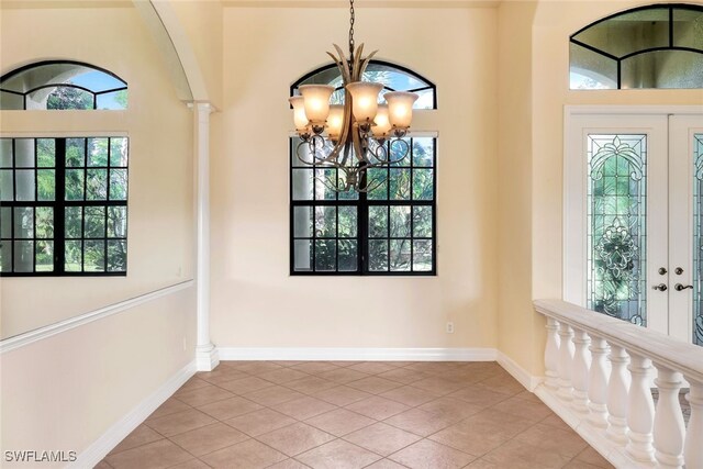 tiled foyer entrance with ornate columns and a chandelier