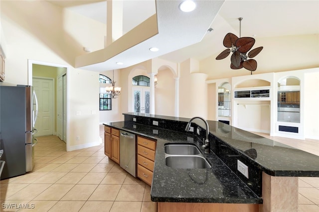 kitchen with dark stone countertops, sink, stainless steel appliances, and a large island with sink