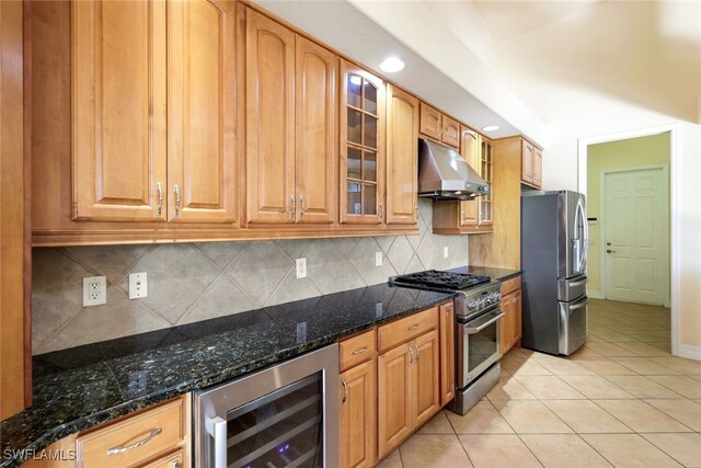 kitchen featuring stainless steel appliances, beverage cooler, tasteful backsplash, dark stone countertops, and light tile patterned floors