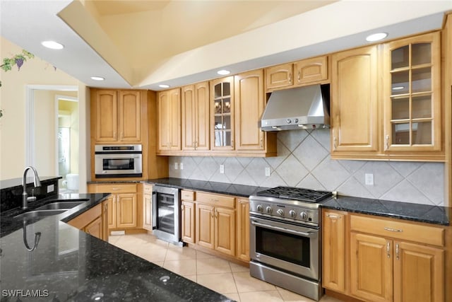 kitchen featuring dark stone countertops, light tile patterned floors, appliances with stainless steel finishes, range hood, and beverage cooler