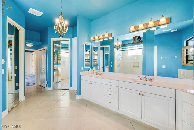 bathroom featuring tile patterned flooring, a notable chandelier, an enclosed shower, and vanity