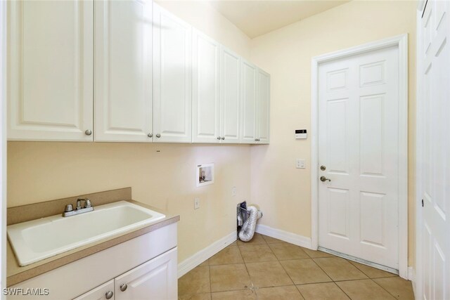 washroom with cabinets, sink, light tile patterned flooring, and washer hookup