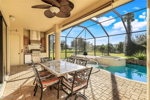 view of patio / terrace featuring glass enclosure, ceiling fan, an outdoor kitchen, grilling area, and a swimming pool with hot tub