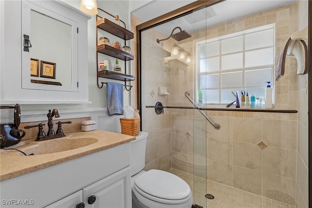 bathroom featuring a shower with door, vanity, and toilet