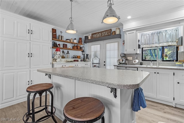 kitchen featuring white cabinets, a kitchen breakfast bar, light hardwood / wood-style flooring, and hanging light fixtures