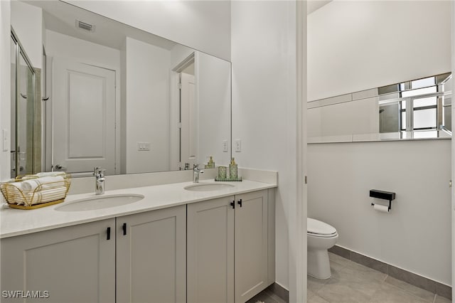 bathroom featuring tile patterned flooring, vanity, toilet, and a shower with door