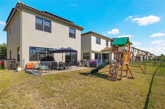 rear view of house with a playground, a yard, and a patio